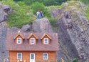 People stand on a cliff above a house
